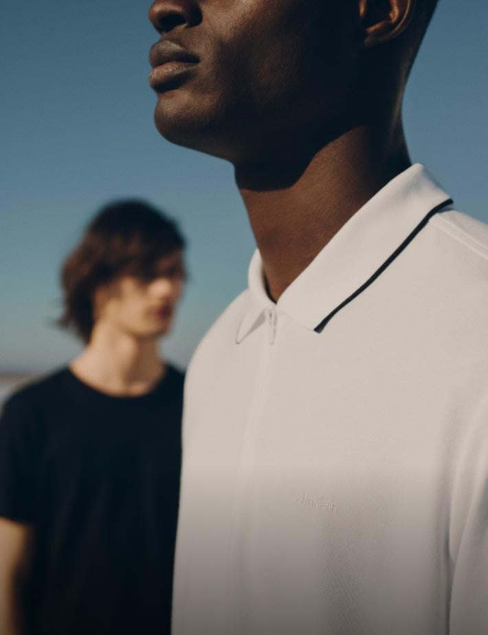 Two men wearing shirts - a white polo and a black tee