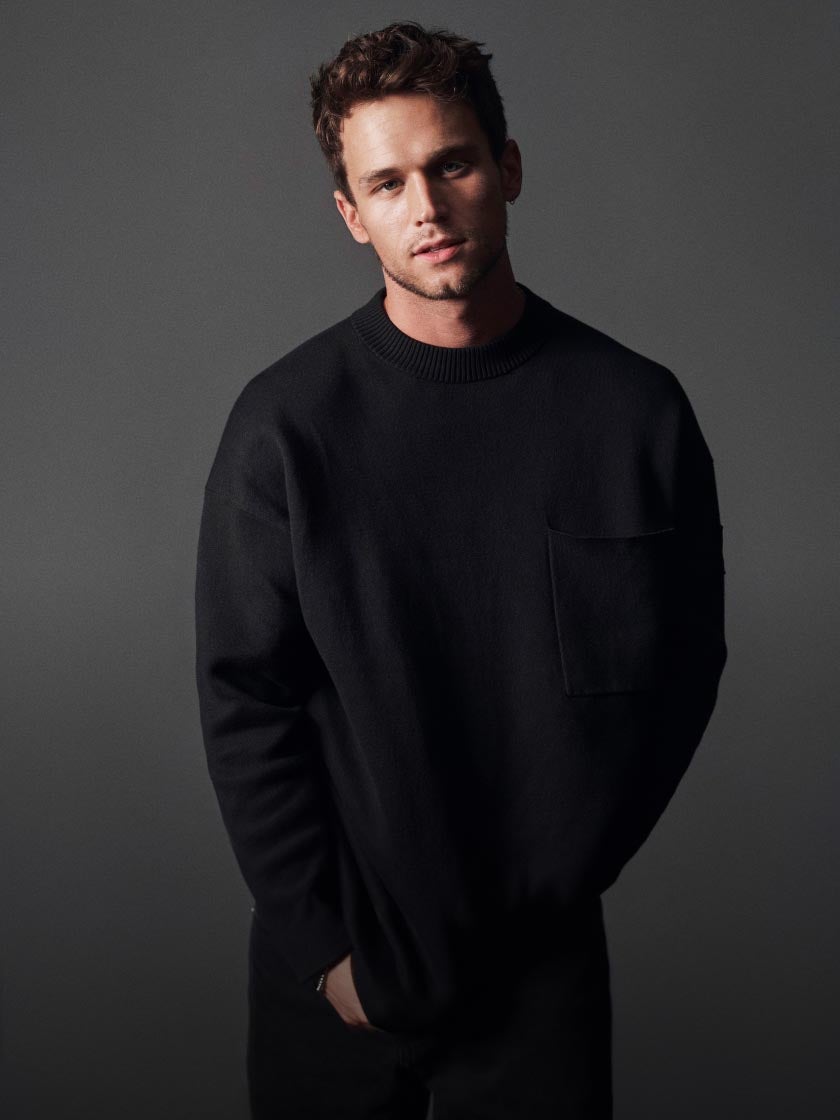 Brandon Flynn wearing a black oversized sweater