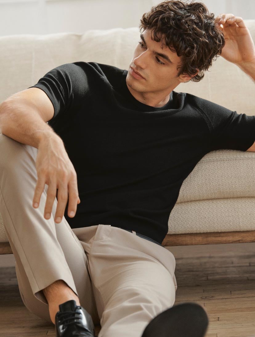 Man sitting on the floor wearing a black short sleeve sweater