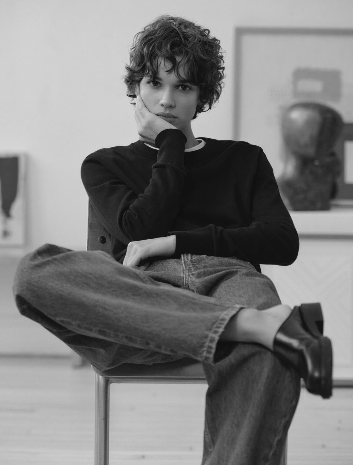 Woman sitting down wearing a black long sleeve sweater