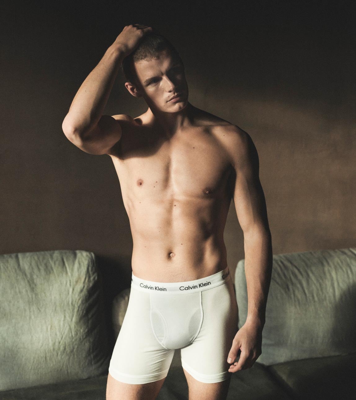 Man posing with his hand on his head wearing white Calvin Klein logo waistband boxer brief underwear
