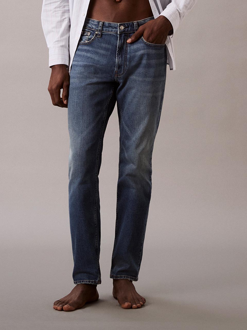 Model wearing head to toe Calvin Klein featuring the slim fit jeans.