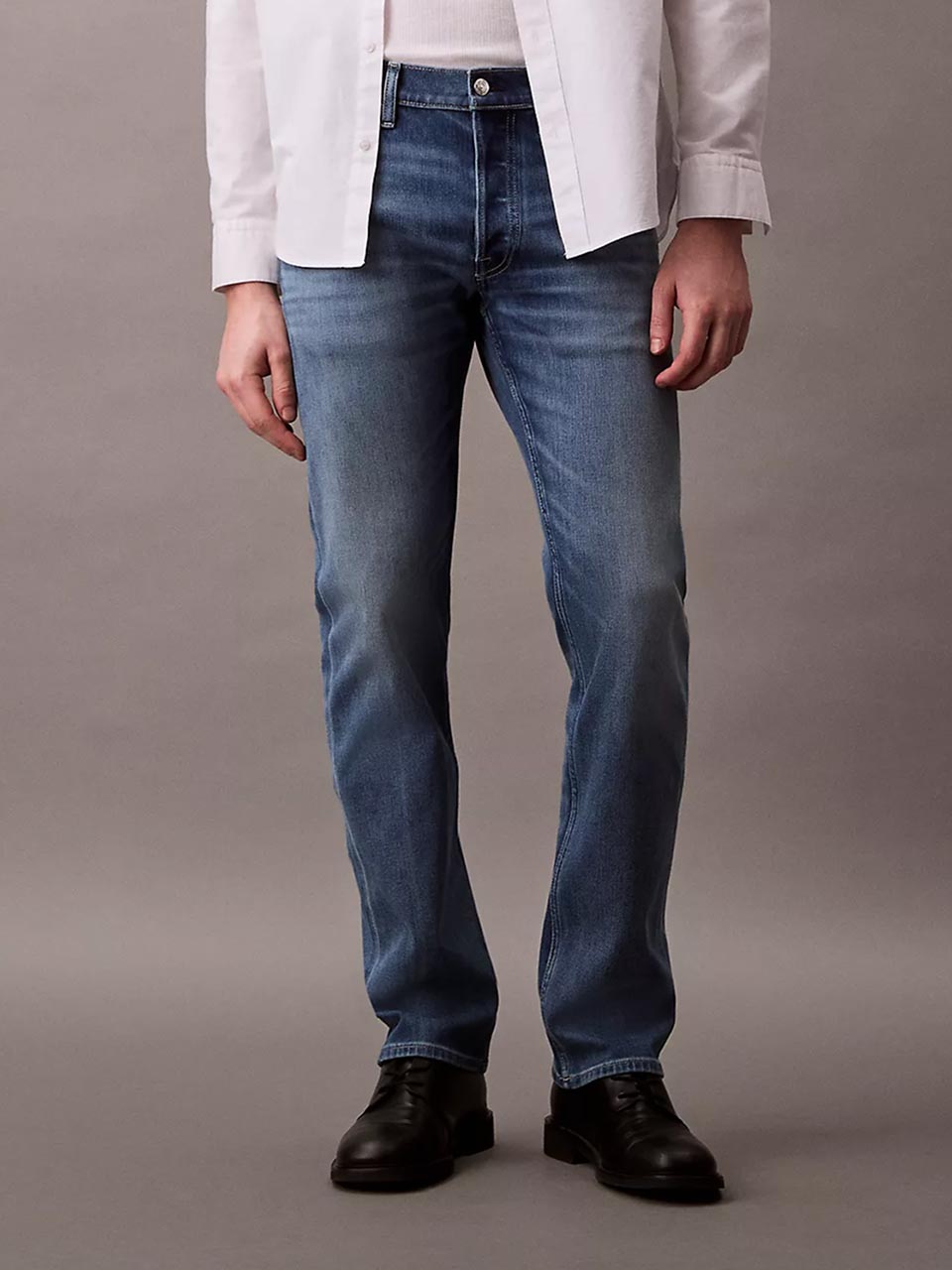 Model wearing head to toe Calvin Klein featuring the slim straight fit jeans.