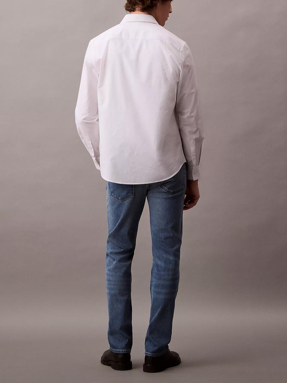 Model wearing head to toe Calvin Klein featuring the slim straight fit jeans.
