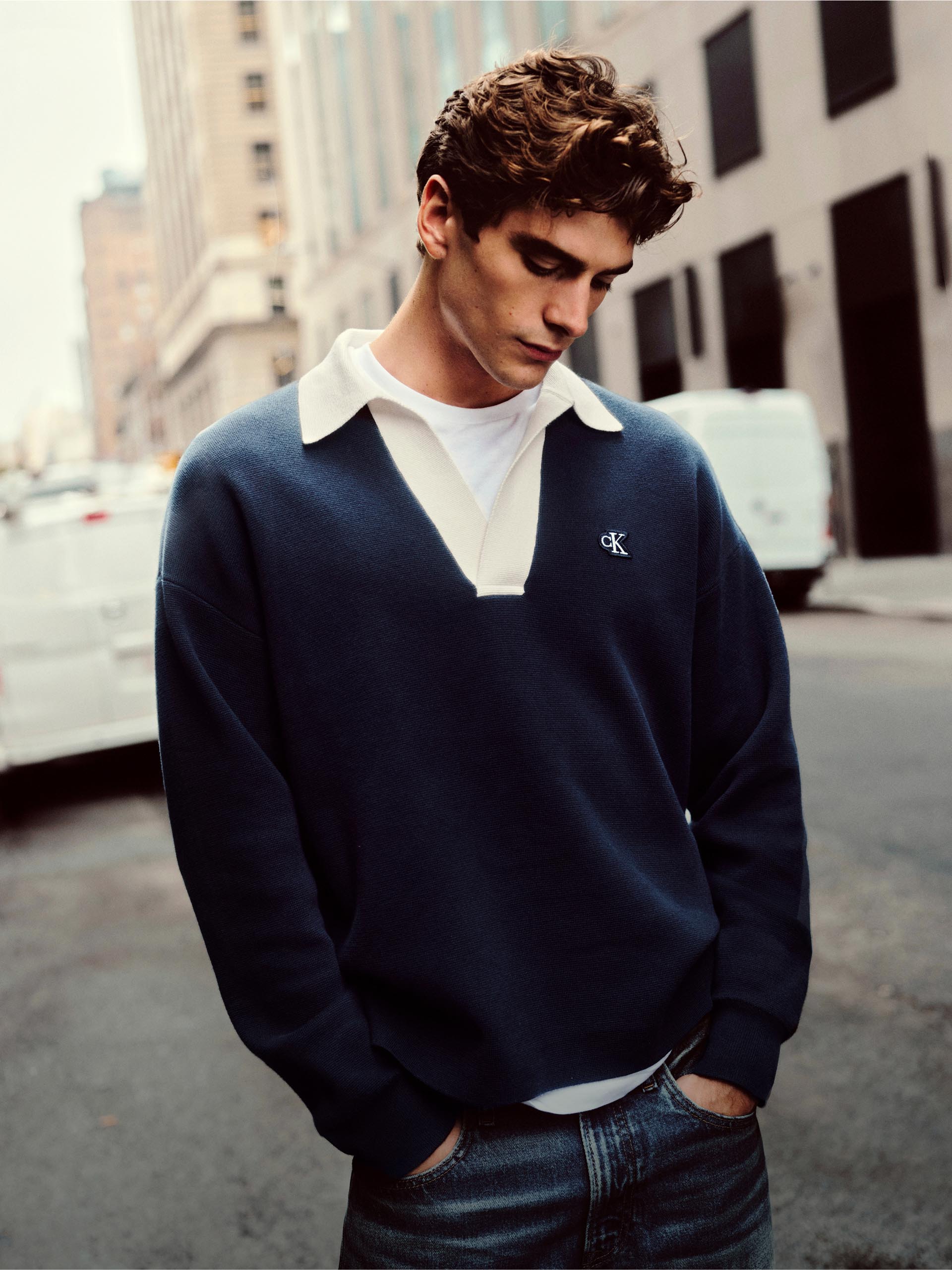 Model wearing a Calvin Klein logo knit weater while out and about in the city.
