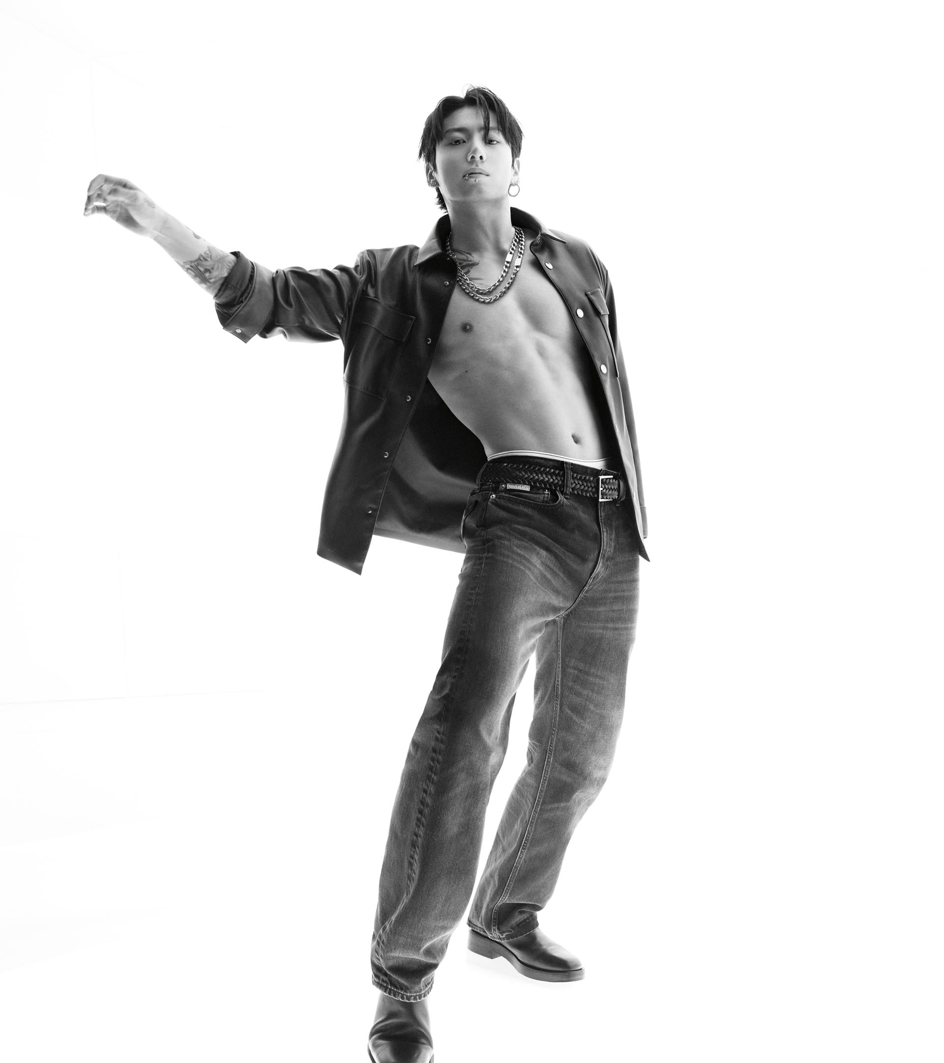 Jung Kook posing in an unbuttoned leather shirt and black straight jeans