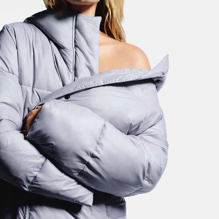 Model posing in a grey puffer coat