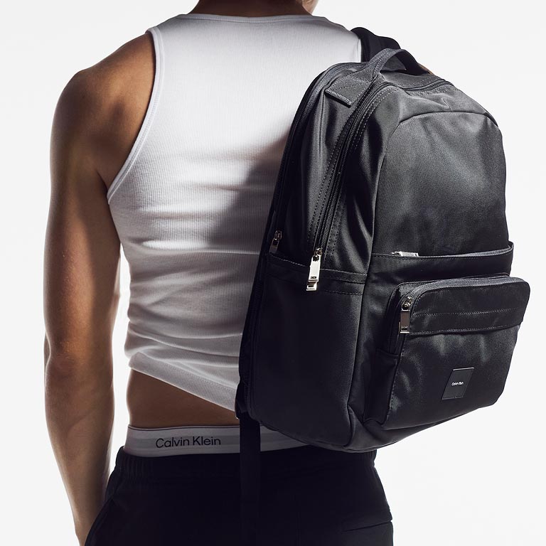 Model posing with a black backpack