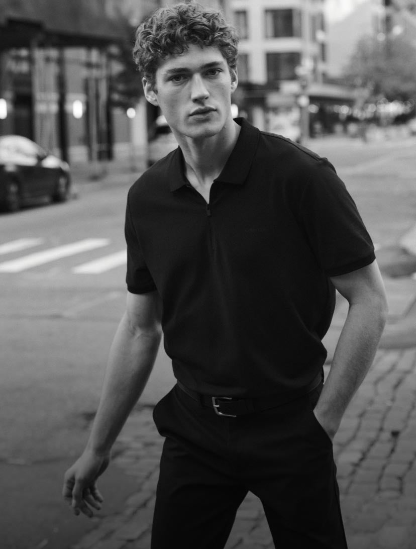 Man with his hand in his pocket wearing a black short sleeve shirt
