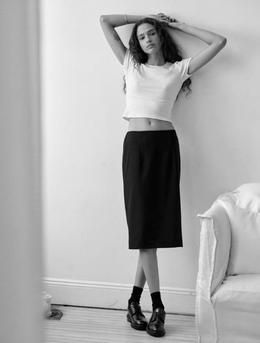 Woman leaning against a wall wearing a black pencil skirt
