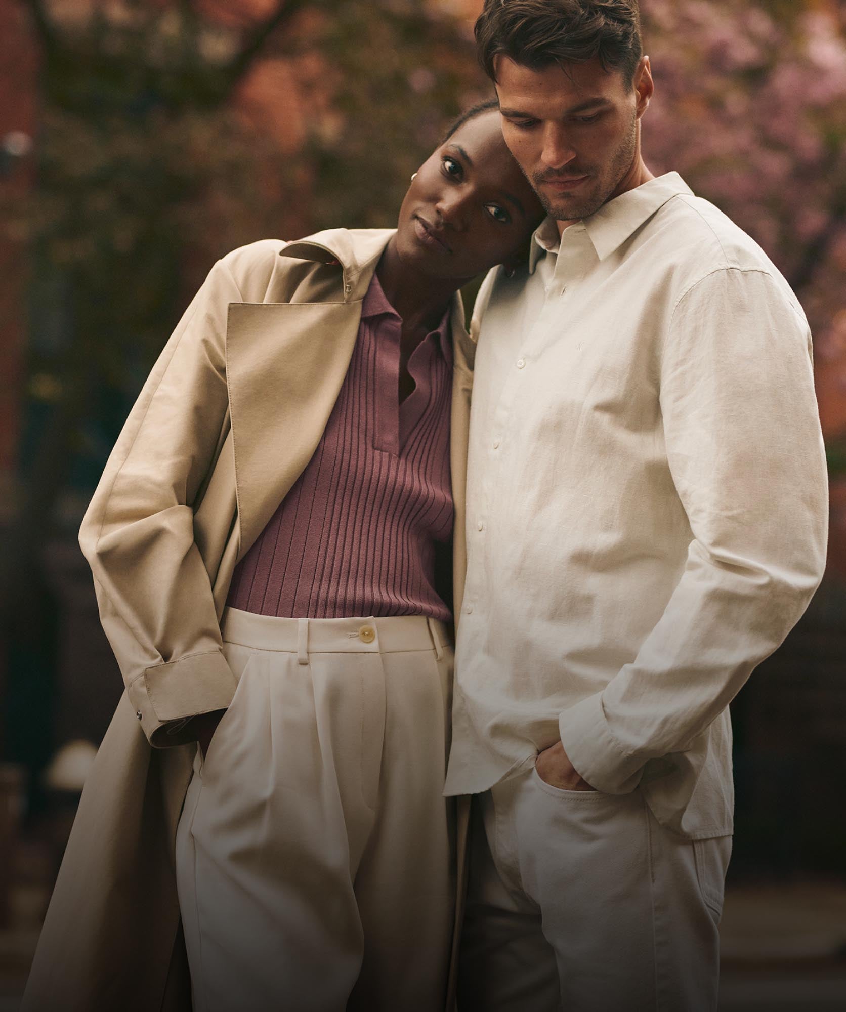 A woman leaning on a man's shoulder, both dressed in Calvin Klein apparel 