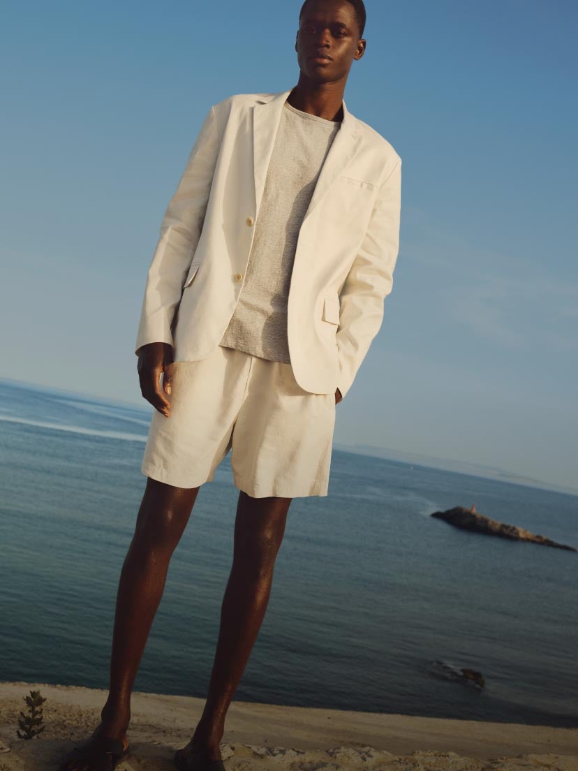 Model posing on the beach wearing a white linen suit