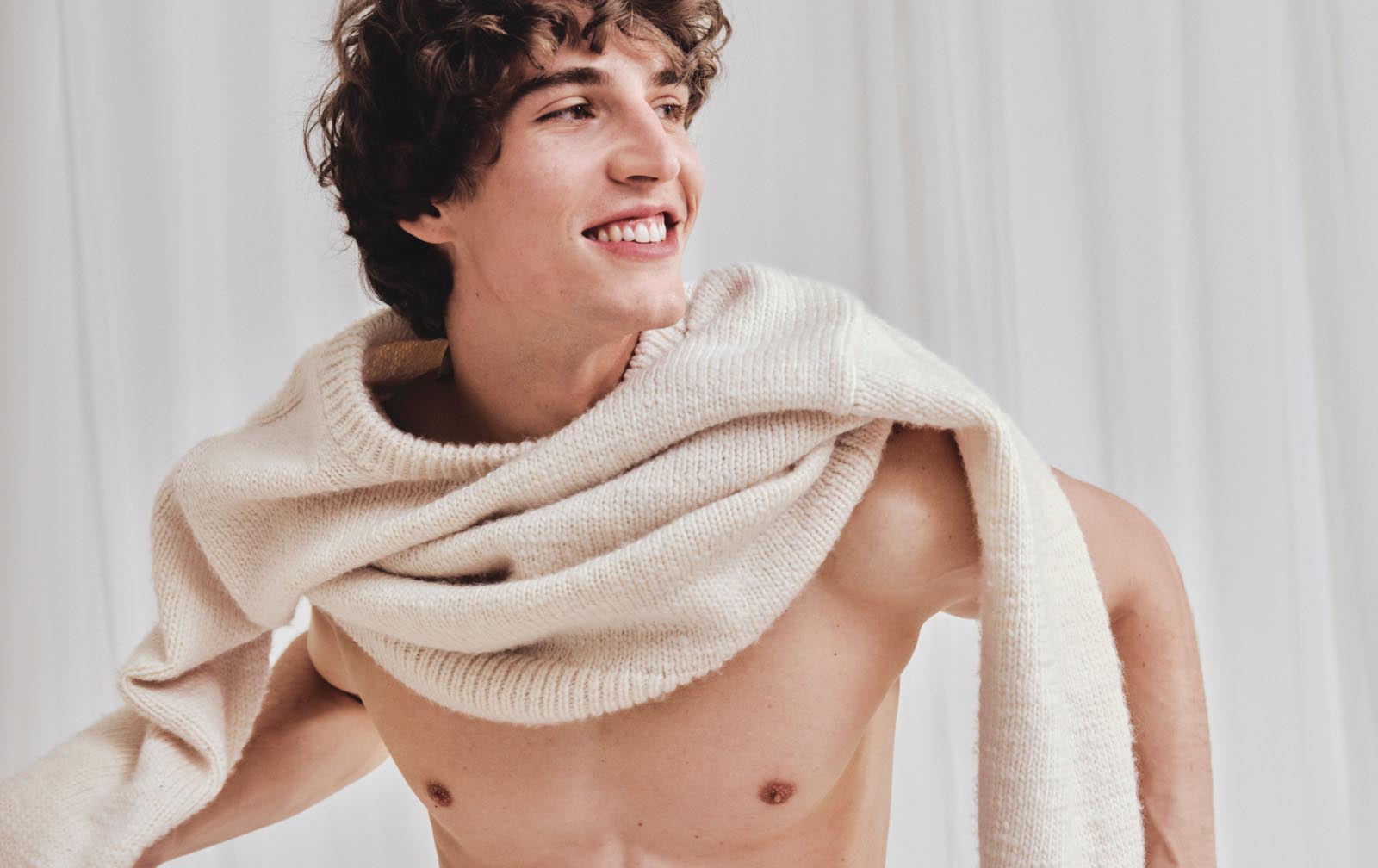 Model posing in a tan coat and tan v-neck sweater