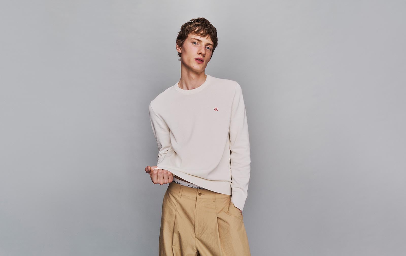 Model posing in a white lightweight sweater and khaki pants