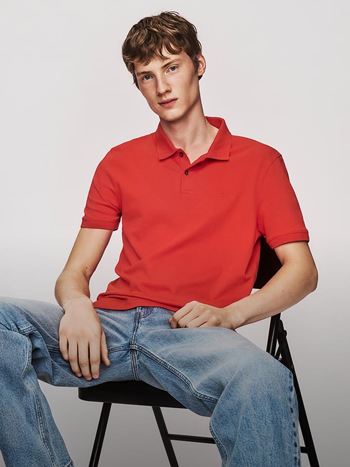 Model posing in a red polo shirt