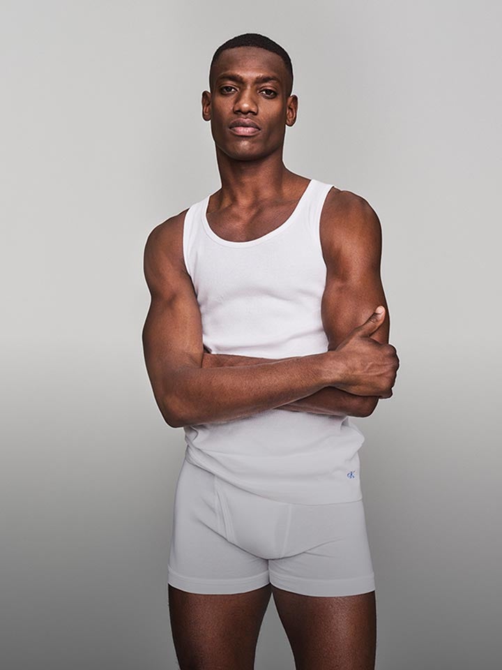 Model posing in a white tank top and white trunk underwear