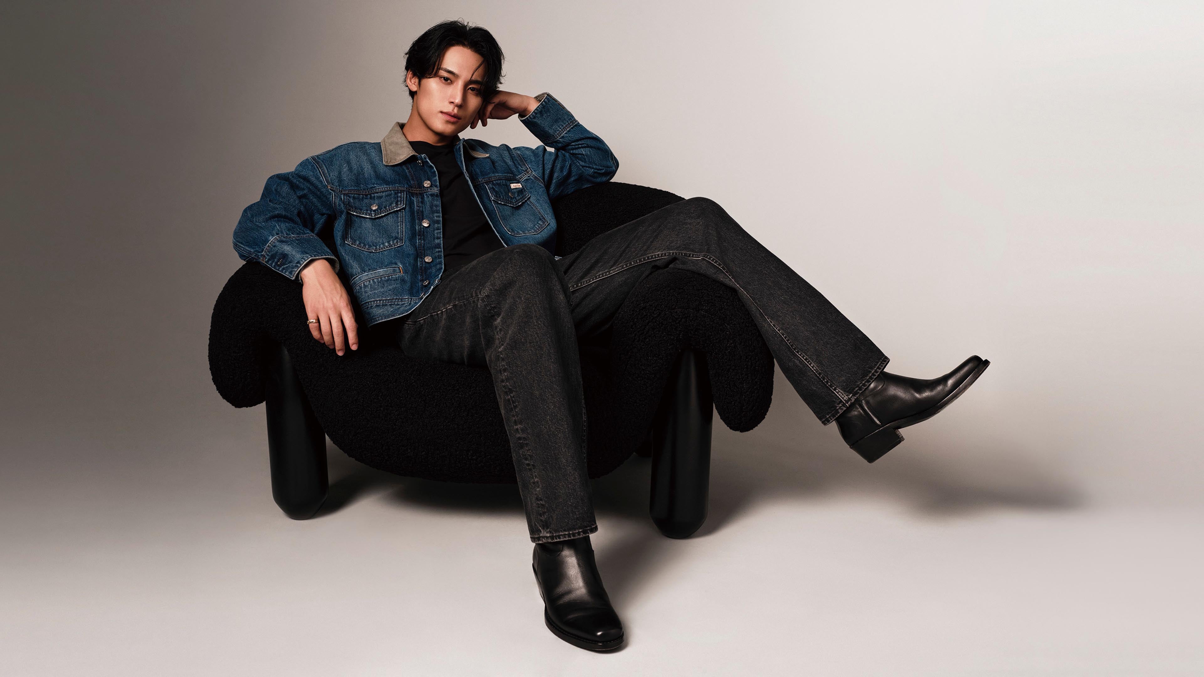 Mingyu posing on a chair wearing Calvin Klein denim 