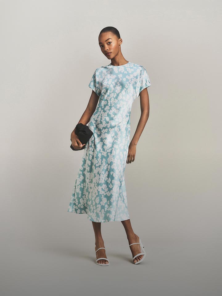 Model posing in a blue and white pattern midi dress.