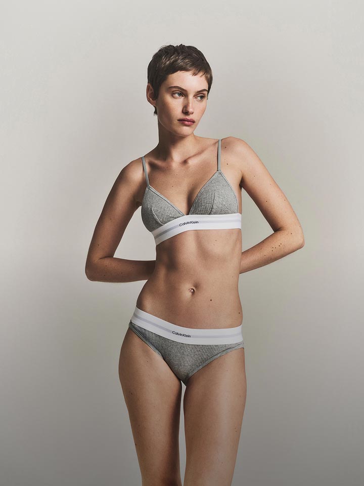 Model posing in a grey bralette & bikini with a Calvin Klein Logo.