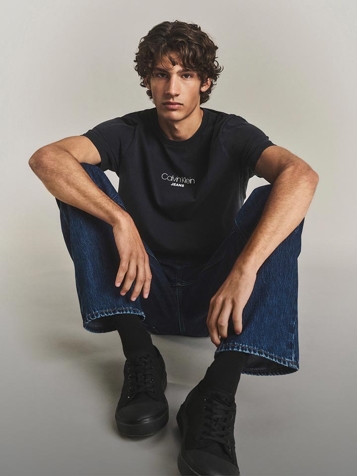 Model posing in a blue t-shirt and denim jeans.