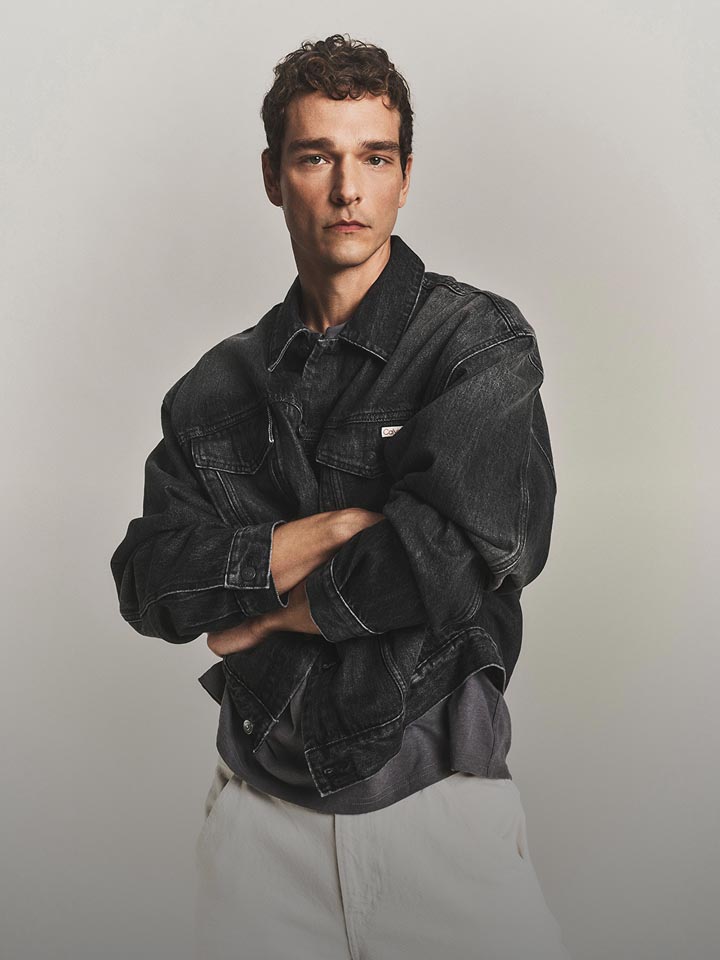 Model posing in a black denim trucker jacket.