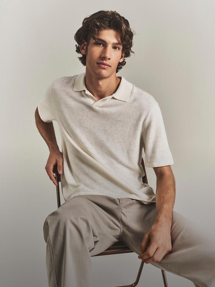 Model posing in a white polo shirt.