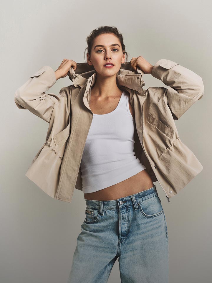 Model posing in a khaki lightweight jacket and jeans.