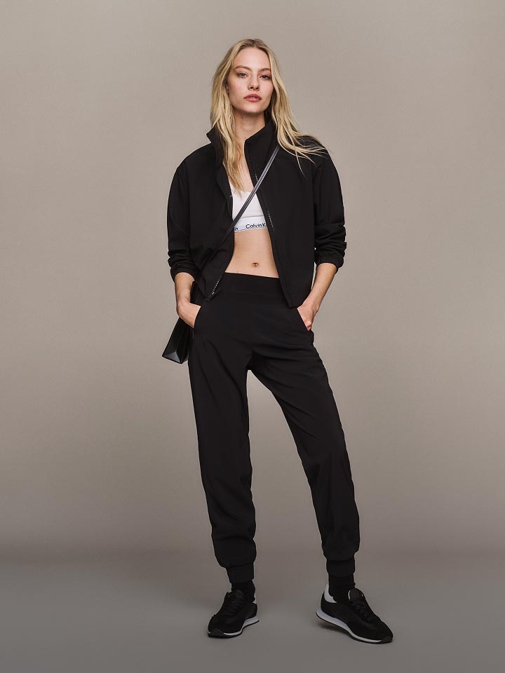 Model posing in a black zip up sweatshirt and joggers.