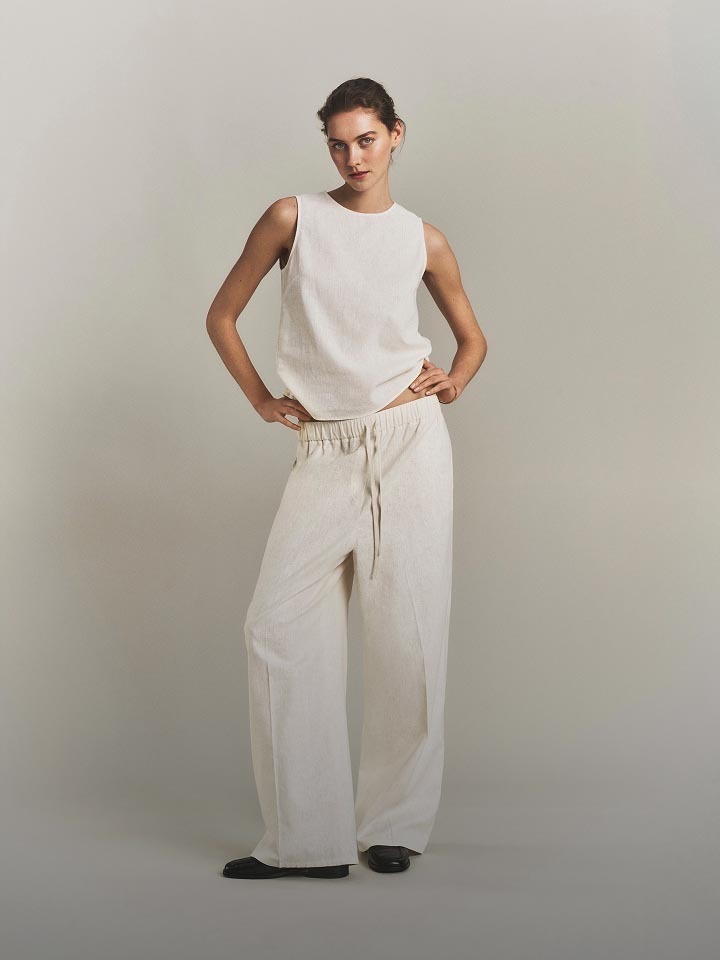 Model posing in a white tank blouse.