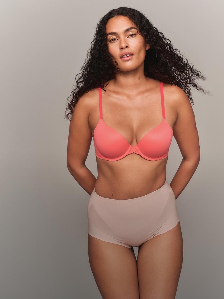 Model wearing a pink t-shirt bra and hipster shapewear.