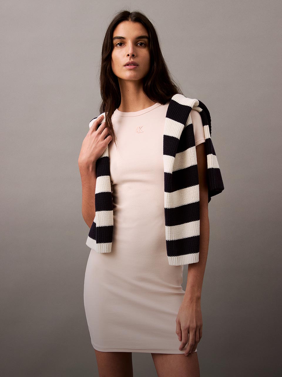 Model posing in the contour rib dress with stripe sweater on top.