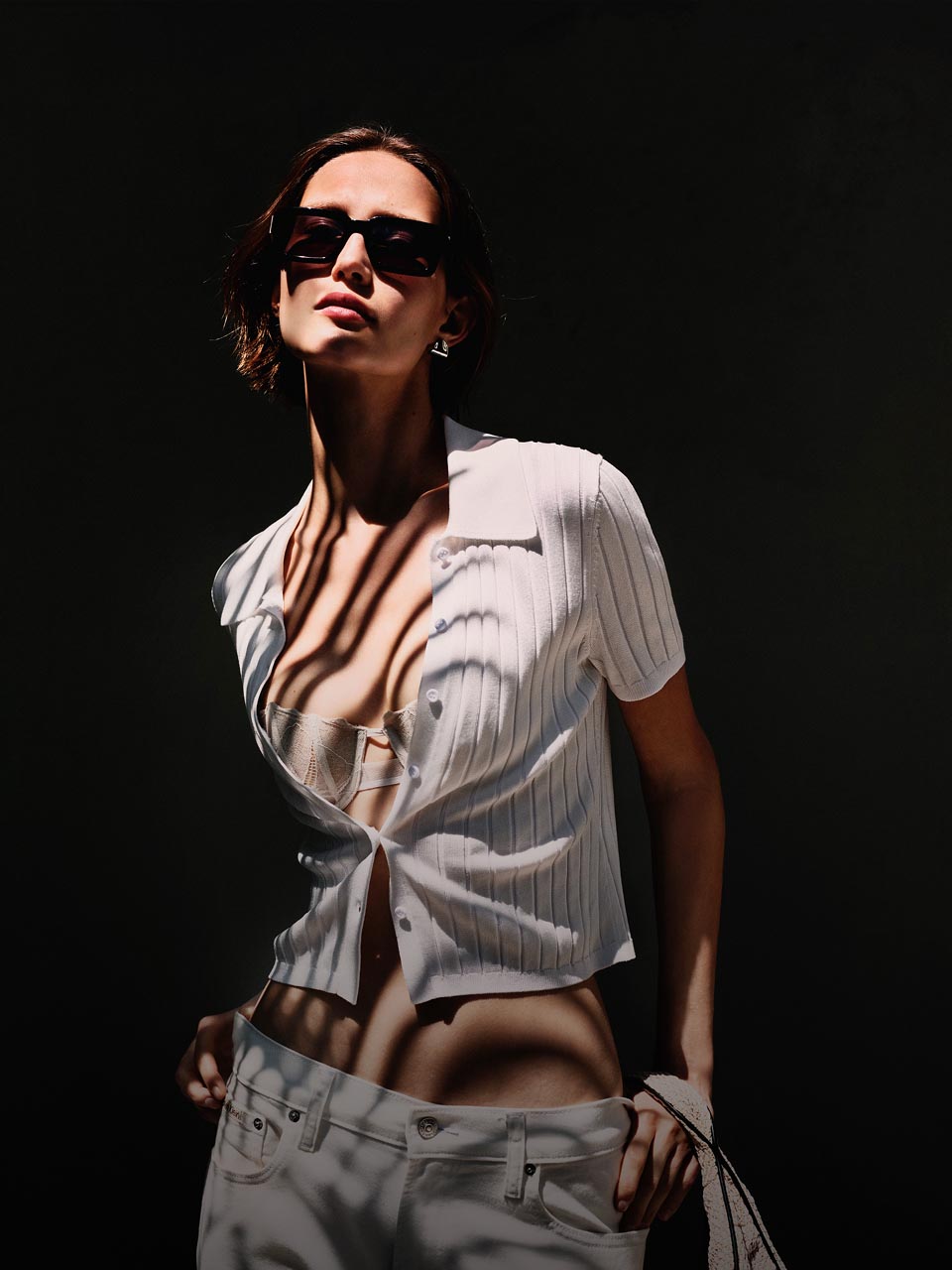 Model posing in a yellow sweater and khaki shorts.