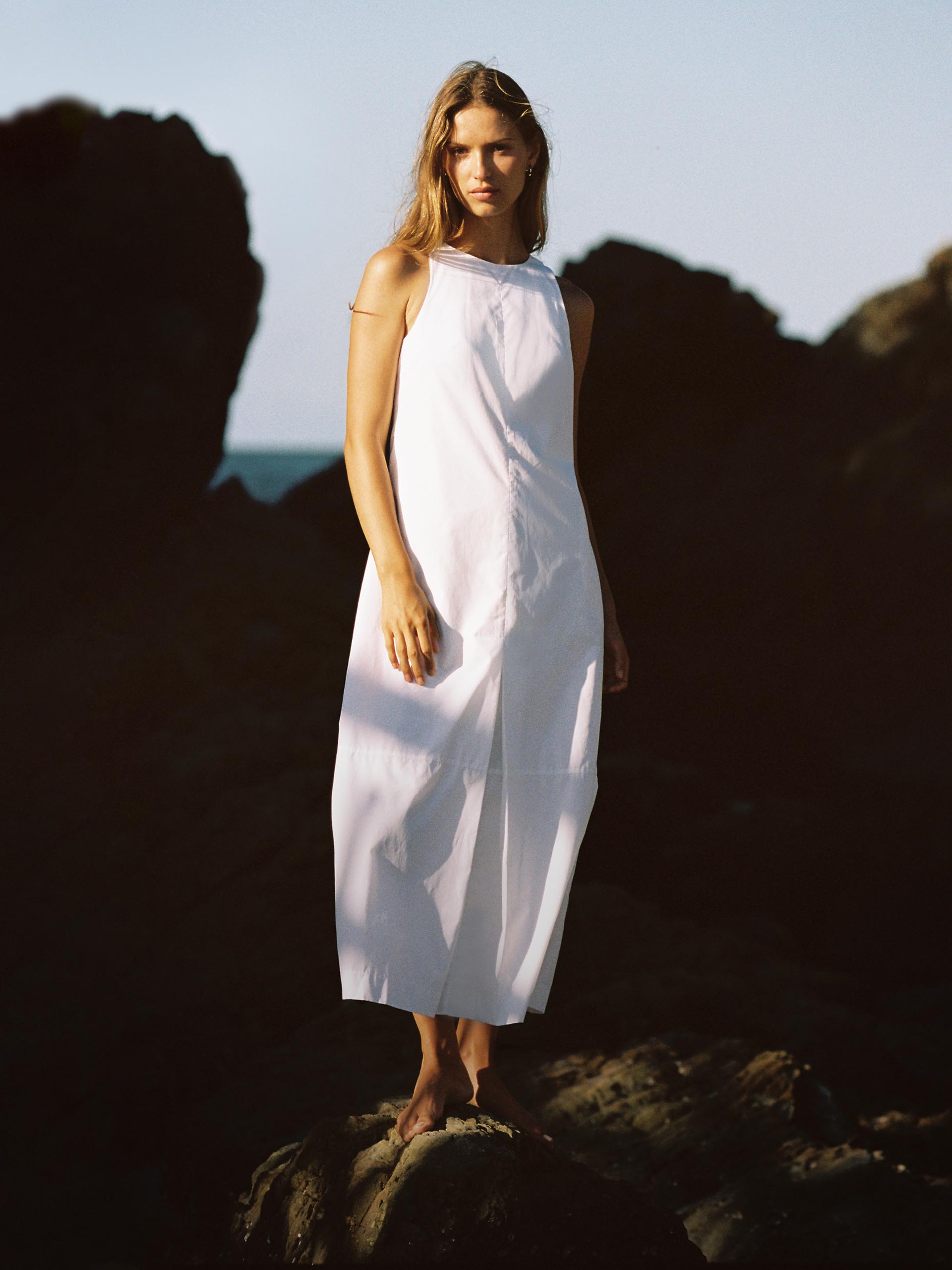 Female model wearing a white dress at the beach