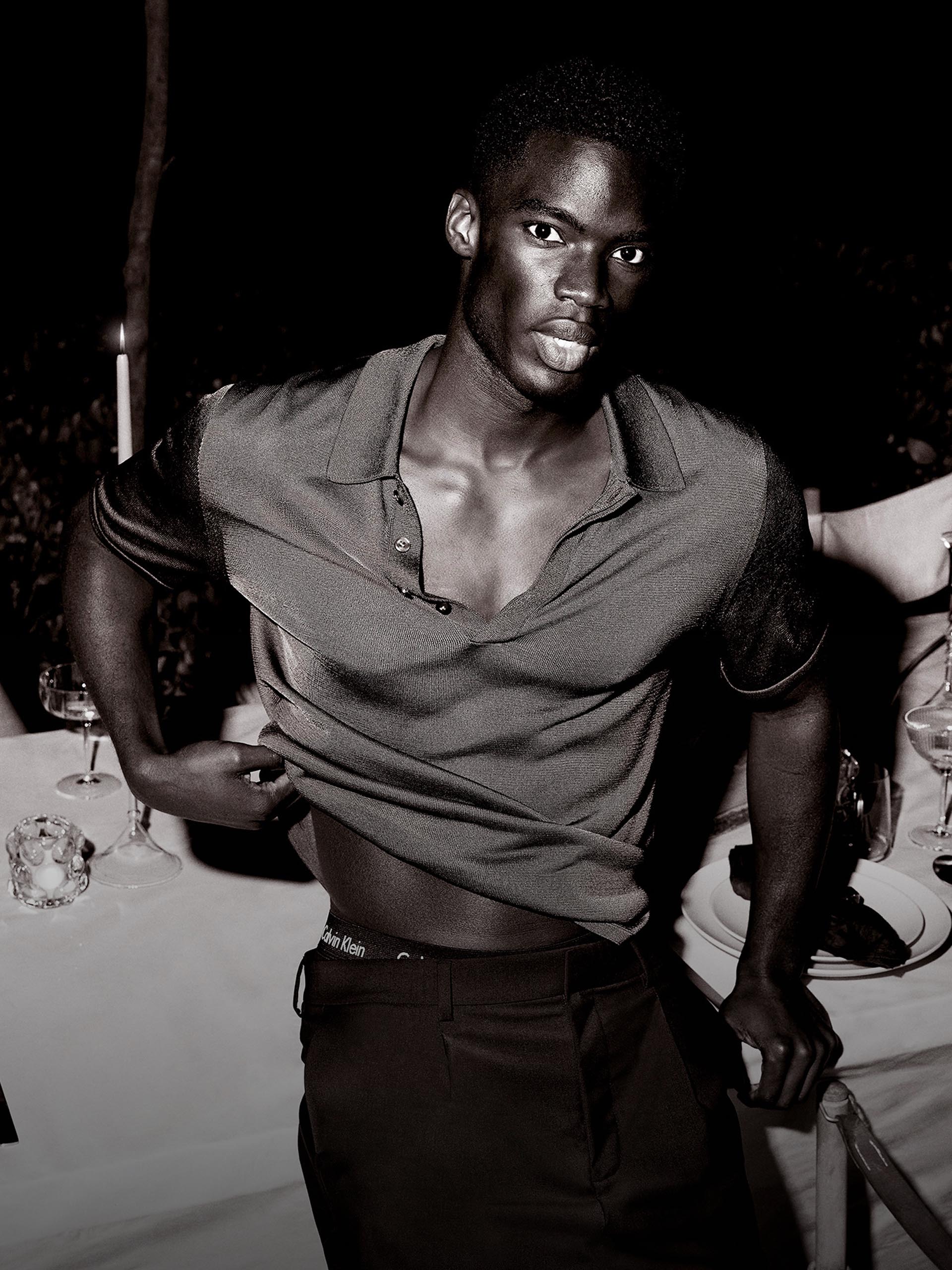Model wearing an evening out short sleeve polo while leaning on a dinner table during a party