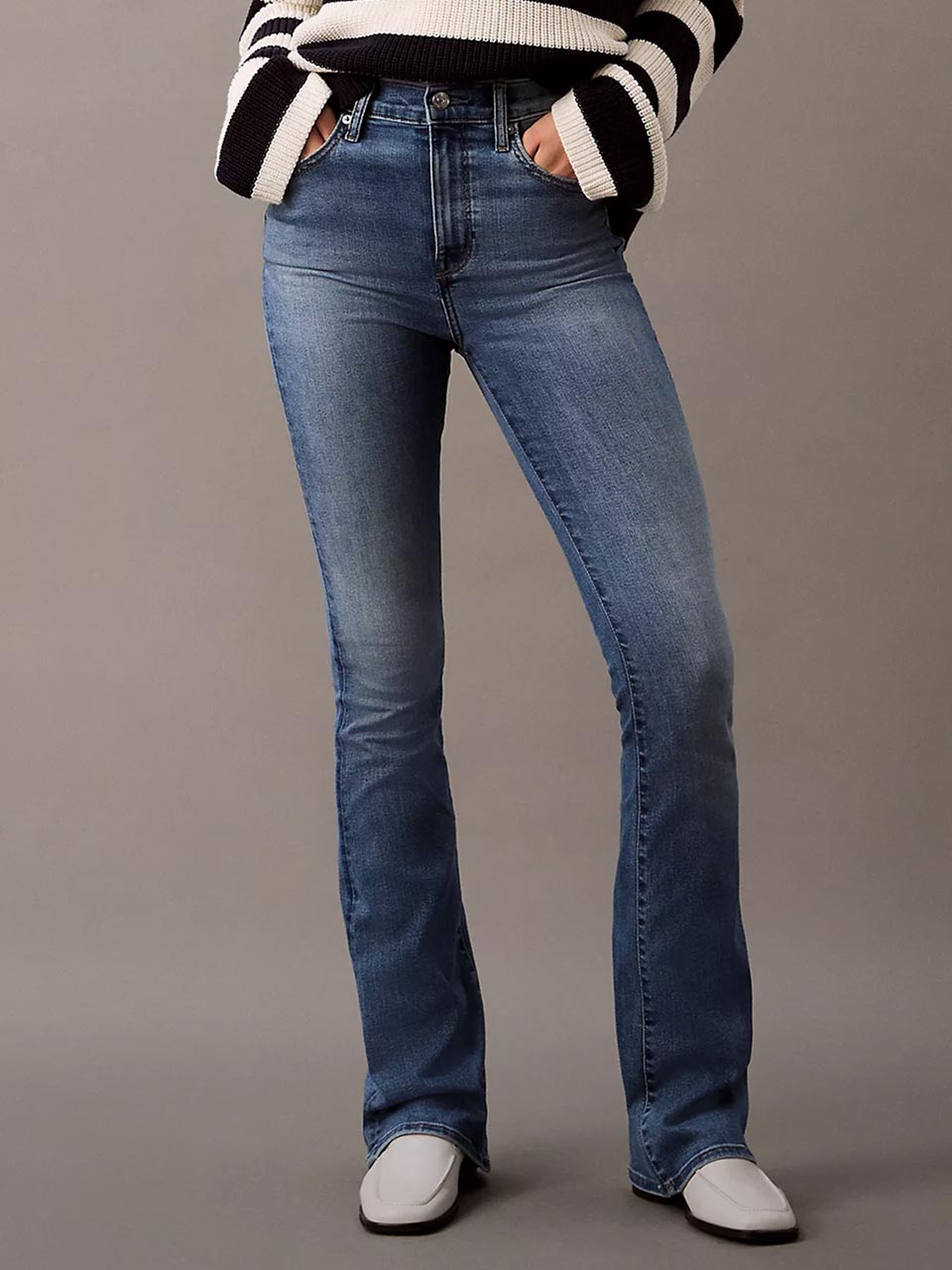 Model wearing head to toe Calvin Klein featuring the high rise flare jeans.