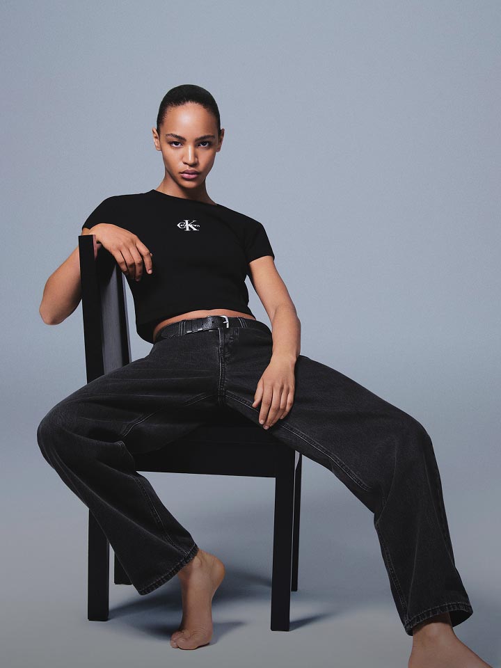 Model wearing black cropped tee with Calvin Klein logo and loose fit black jeans.