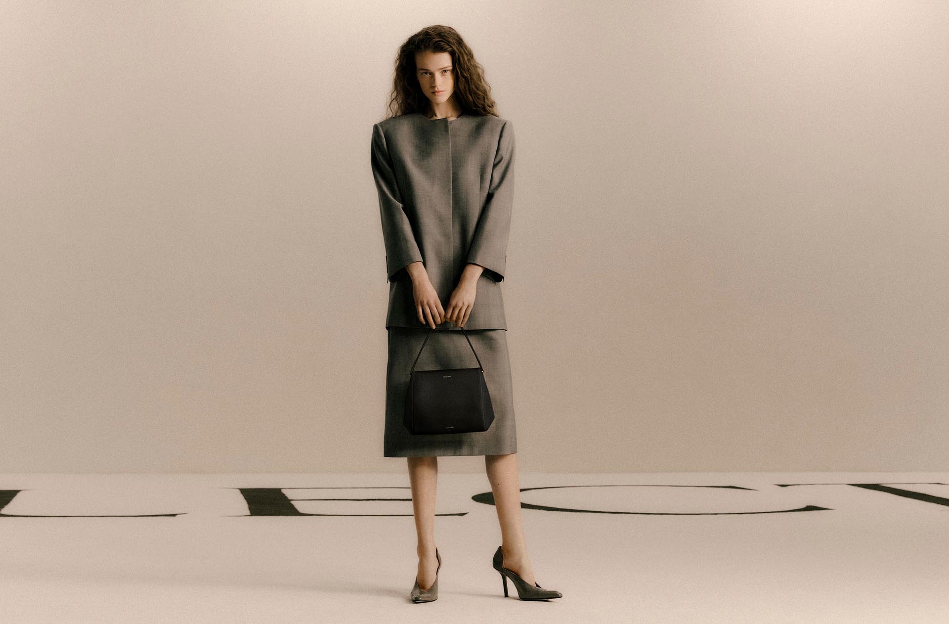 Model carrying a sleek black leather hand bag.
