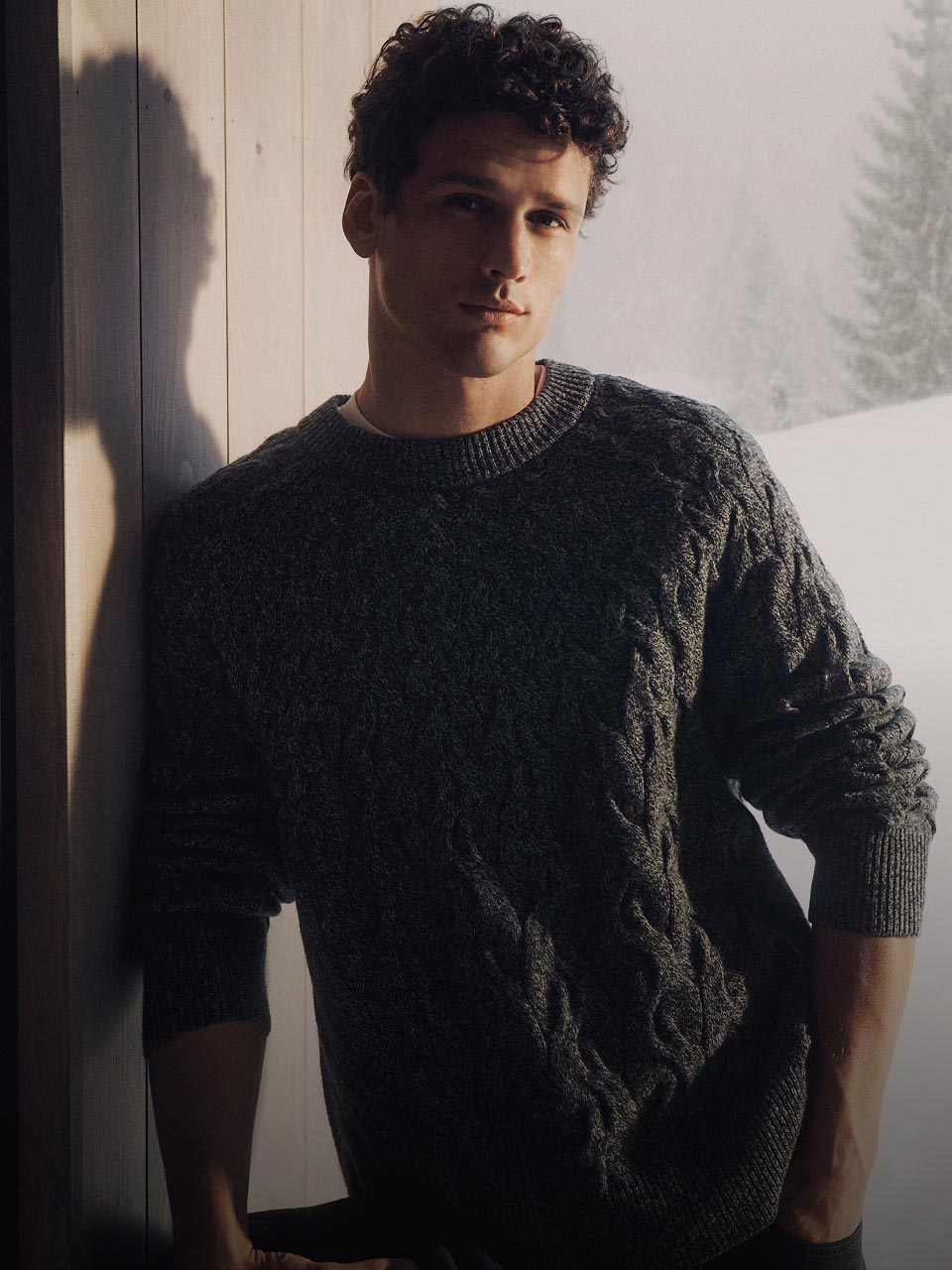 Model posing in a grey cable knit sweater