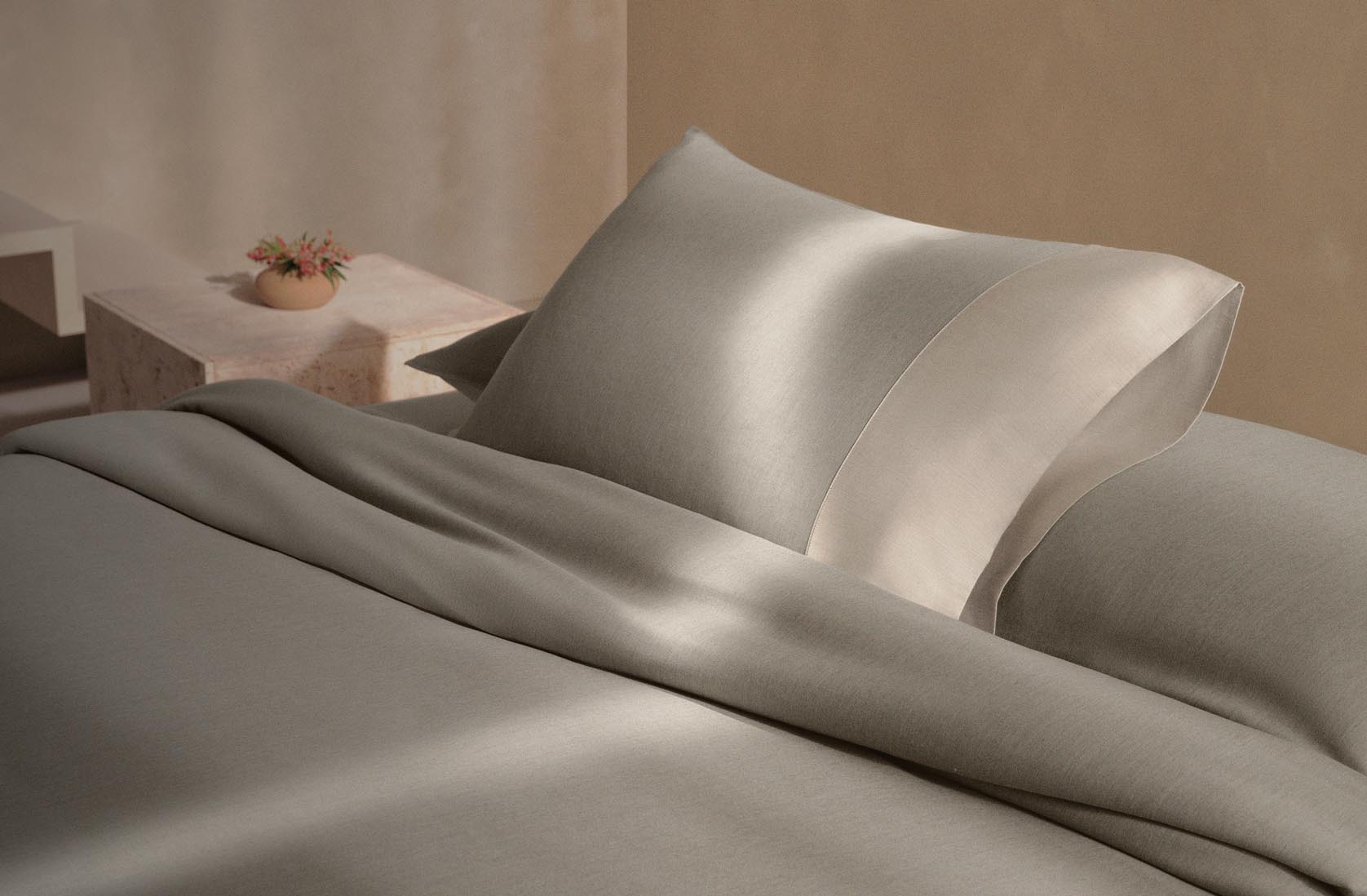 Still life image of a bed with green sheets and comforter