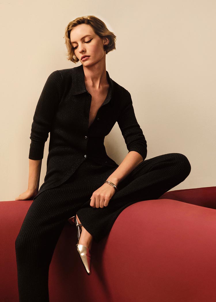 Model posing in a black sweater and black pants