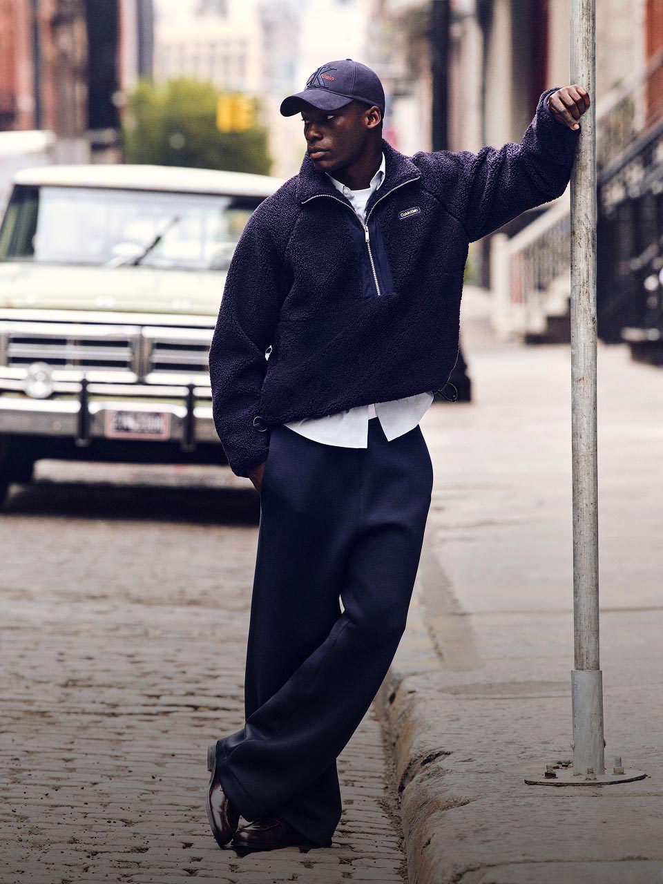 Model posing in a sherpa pullover and blue pants