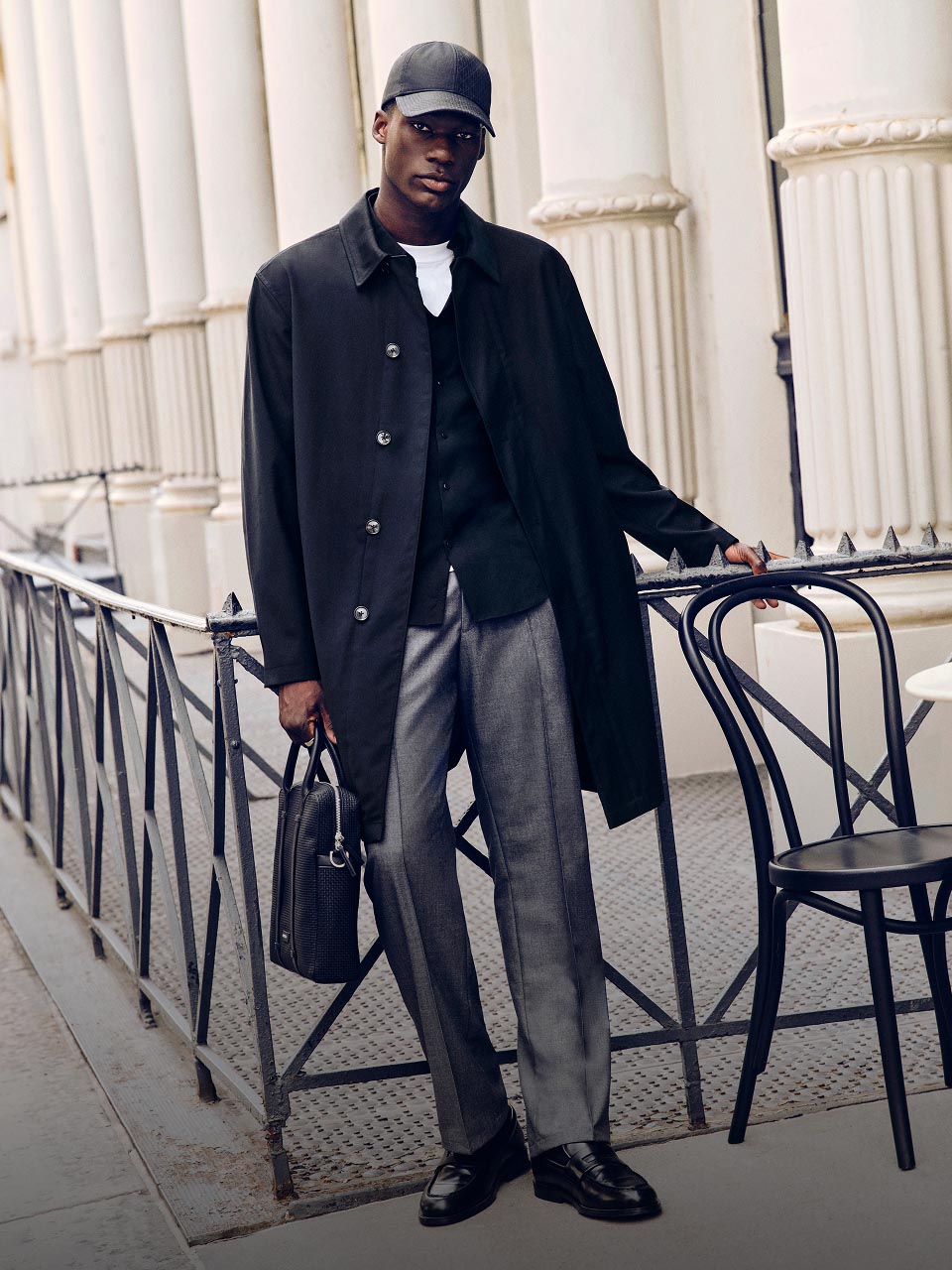 Model posing in a long blue jacket and grey pants