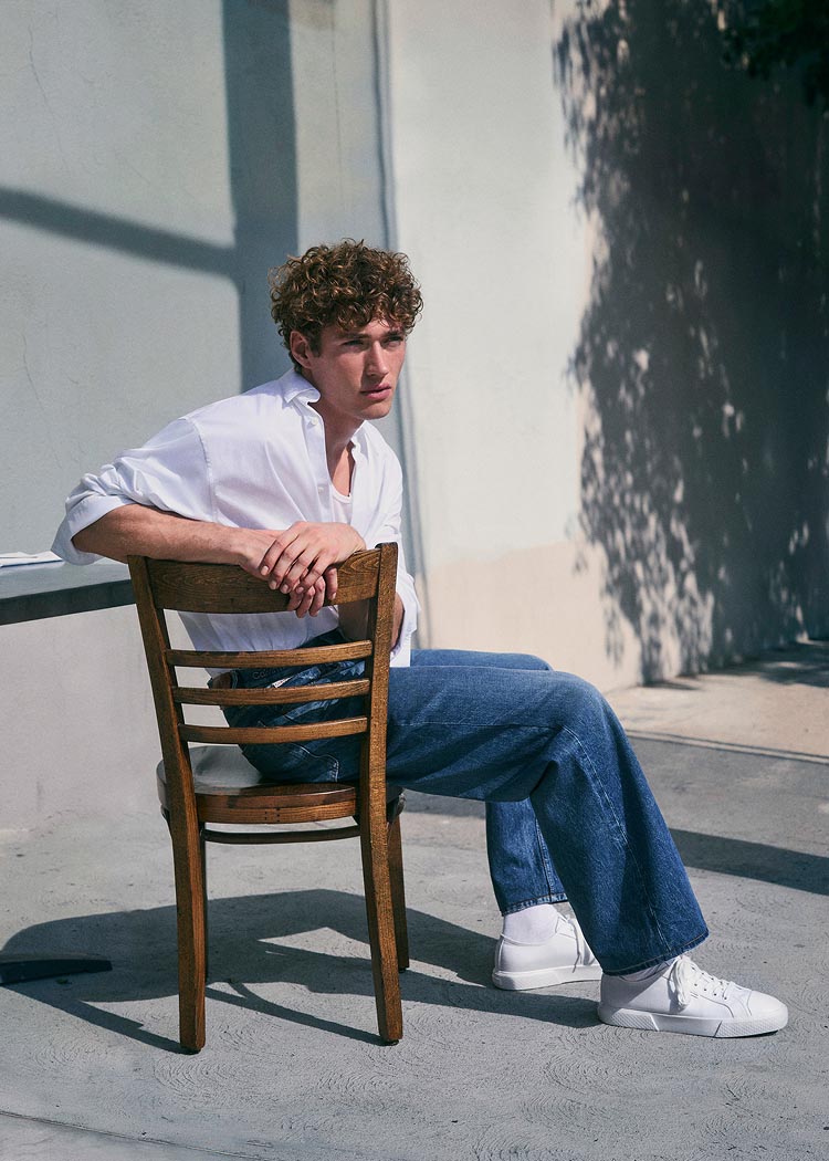 Model posing in a white button-down shirt and jeans