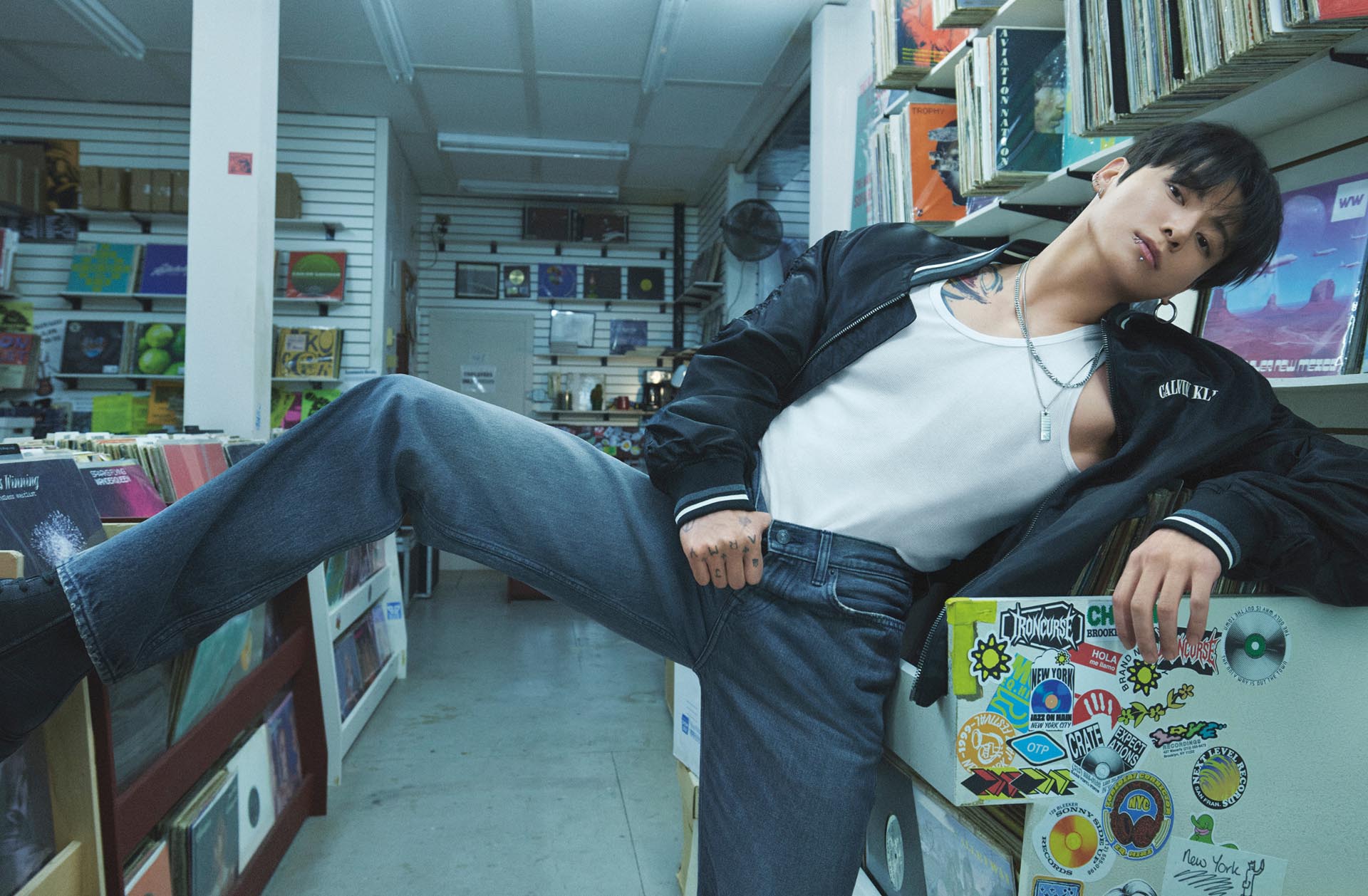 Jung Kook posing in a graphic bomber and medium wash jeans