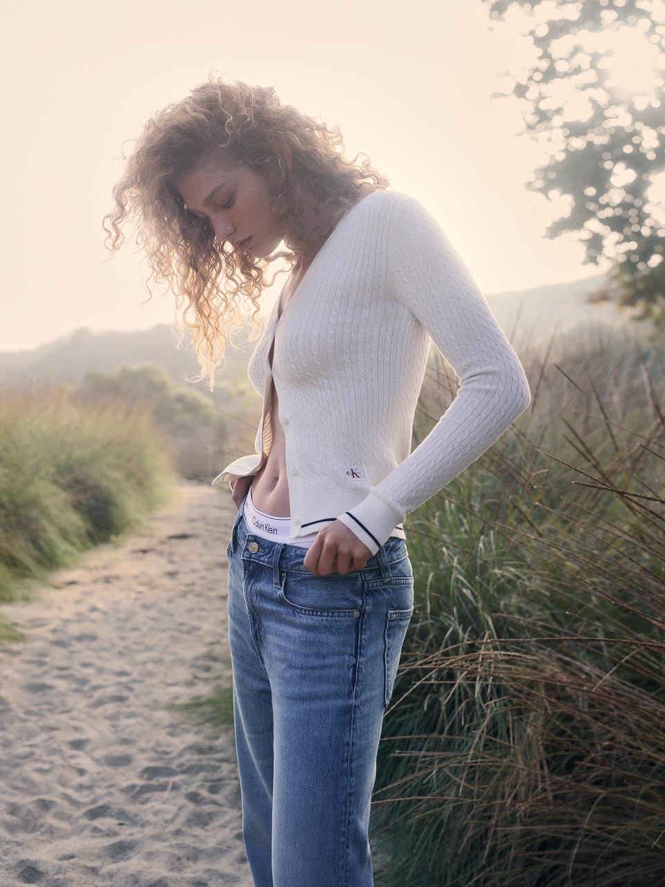 Model posing in a white cardigan sweater