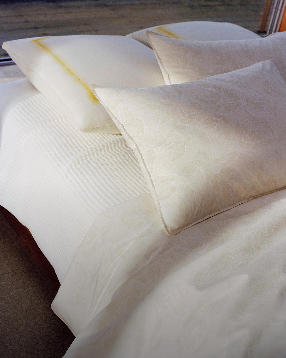 A still life image of a bed with white sheets