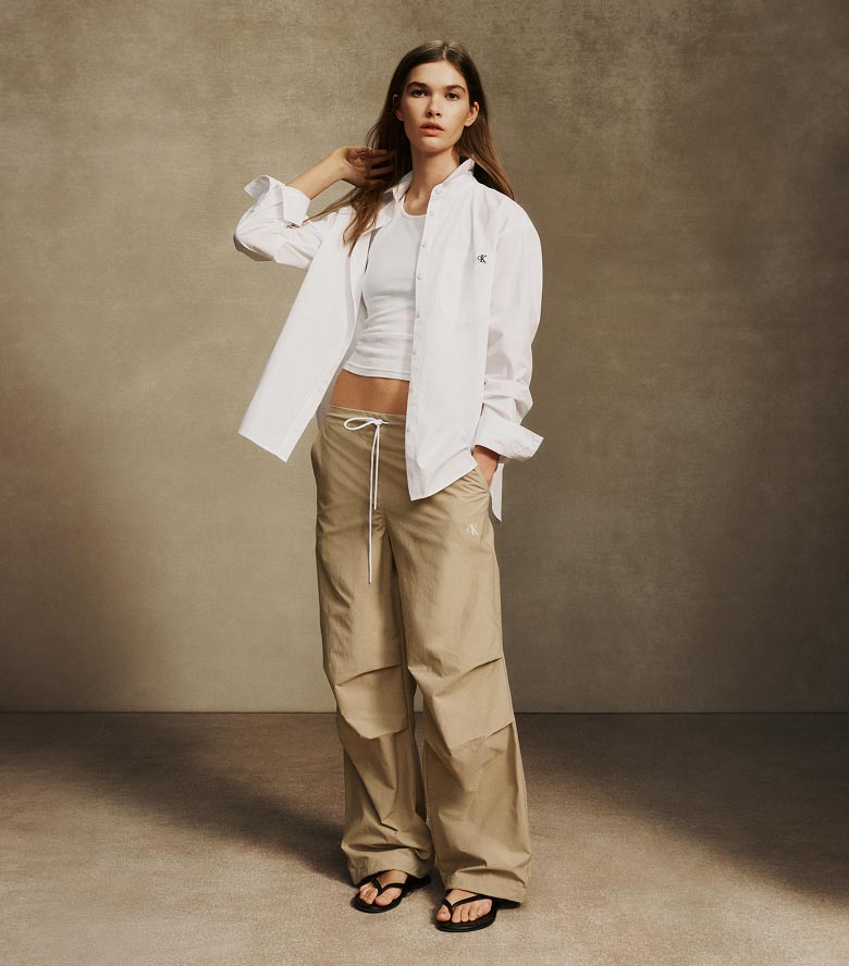 Model posing in tan crinkle nylon pants