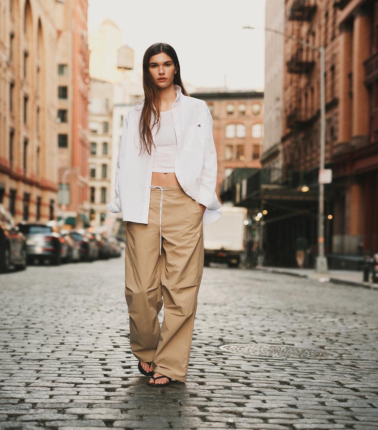 Model posing in tan crinkle nylon pants
