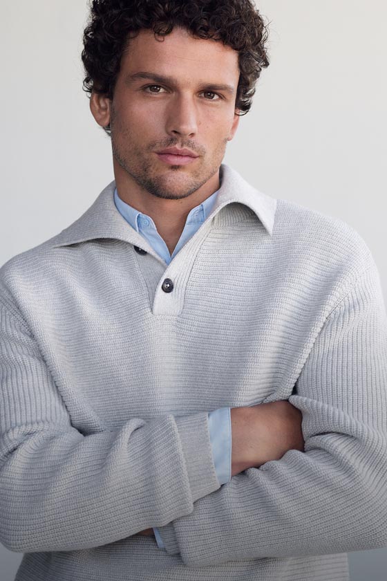 Model posing in a grey ribbed polo sweater