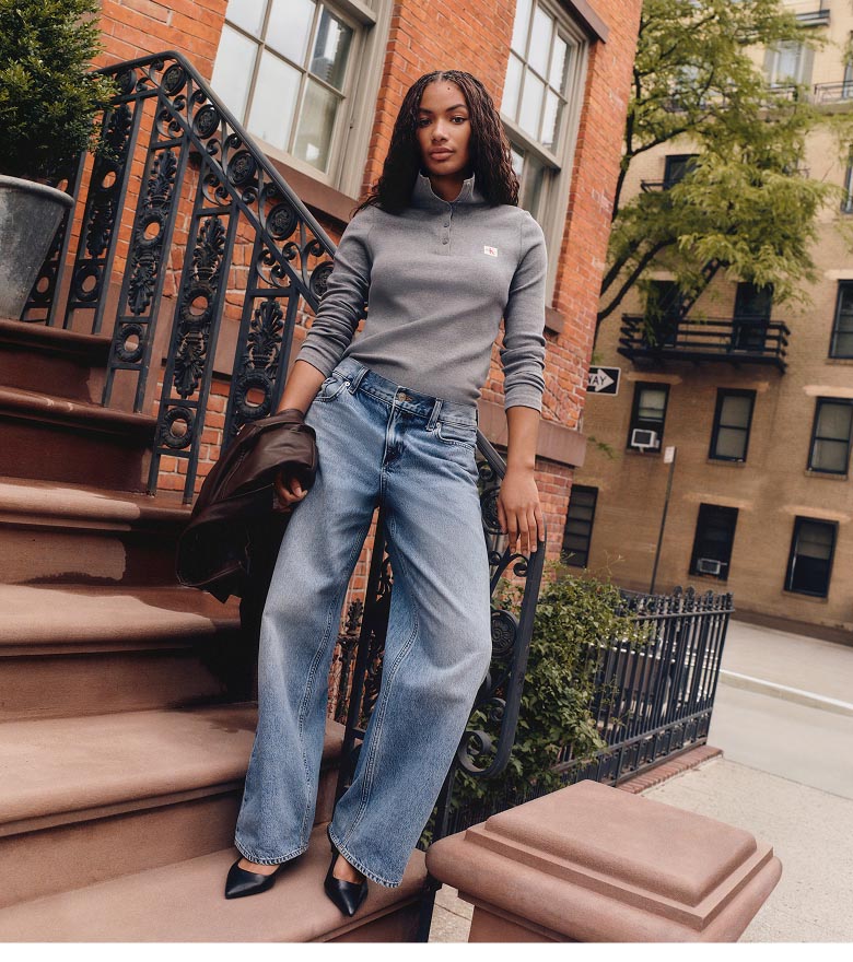 Via posing in a leather overshirt, grey sweatshirt, and baggy jeans